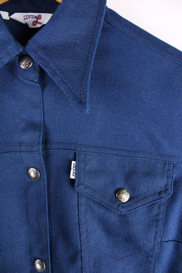 1970s Levi Strauss Trucker/western style jacket in a navy blue colourway. The jacket is one from the Levi's for Gals collection which dates back to 1968. It has two breast pockets, a daggered 1970s style collar and silver buttons. 