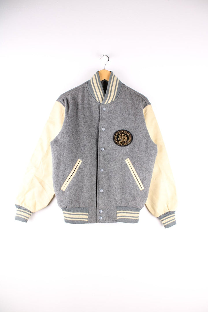 Vintage J Press wool varsity jacket in grey with cream leather sleeves and detailing. The jacket has an elasticated collar and cuffs, jetted pockets and press studs to close. There is a small embroidered patch on the front with a J. Press logo. 