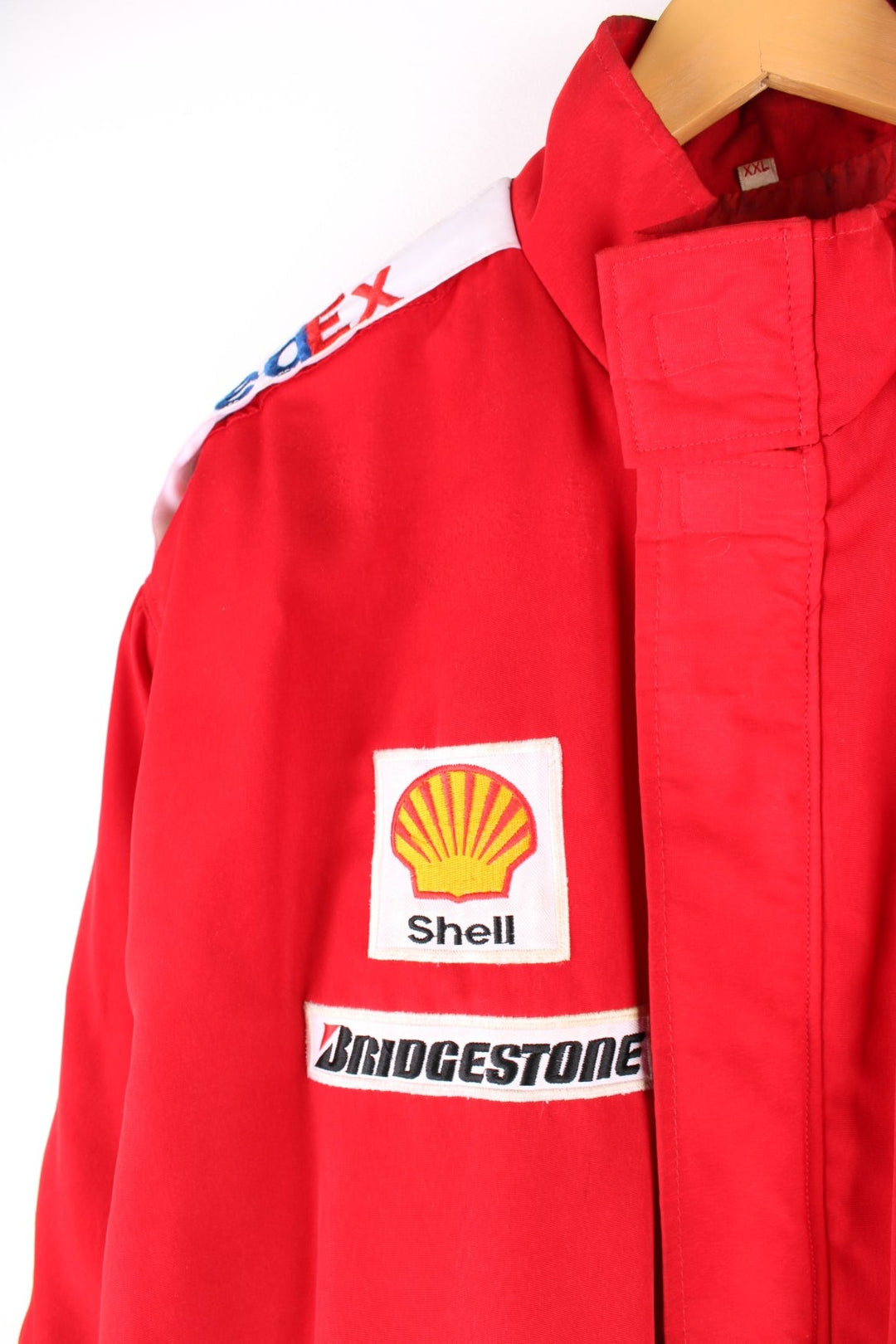 Vintage 2002 Michael Schumacher F1 souvenir jacket in a Ferrari red colourway. The jacket has multiple brand patches down the sleeves, Fed Ex shoulder lapels and a zip/velcro fastening to close. It has a large Marlboro/ Ferrari patch on the back which has to be the most iconic brand collaboration in F1 history. The jacket is dated to 2002, when Schumacher won 11 out of 17 races during the racing season and finished on the podium for all 17. 