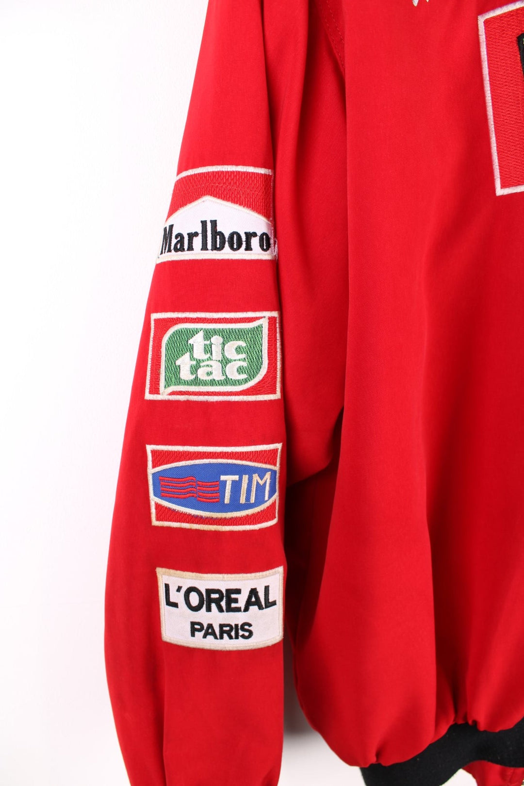 Vintage 2002 Michael Schumacher F1 souvenir jacket in a Ferrari red colourway. The jacket has multiple brand patches down the sleeves, Fed Ex shoulder lapels and a zip/velcro fastening to close. It has a large Marlboro/ Ferrari patch on the back which has to be the most iconic brand collaboration in F1 history. The jacket is dated to 2002, when Schumacher won 11 out of 17 races during the racing season and finished on the podium for all 17. 