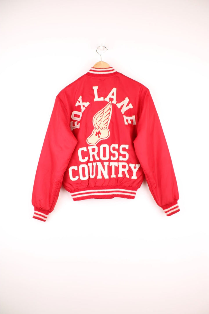 Vintage 1980's 'Birdie' red nylon varsity jacket, features large spell-out motif on the back 'Fox Lane Cross Country' in white. Also has personalised name on the chest and popper button fastening