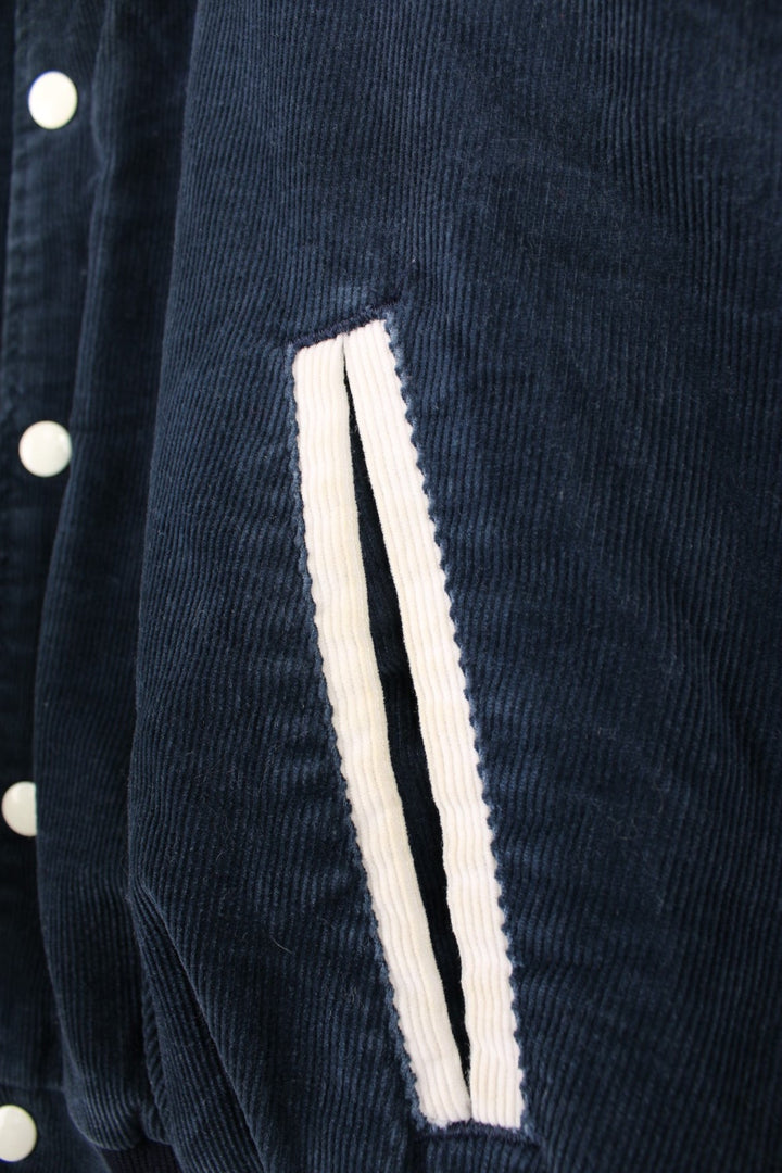 Vintage 90's navy blue corduroy varsity jacket by Rennoc. Features embroidered spell-out motif on the back 'Swim Team' in white, popper buttons fastenings and quilted lining