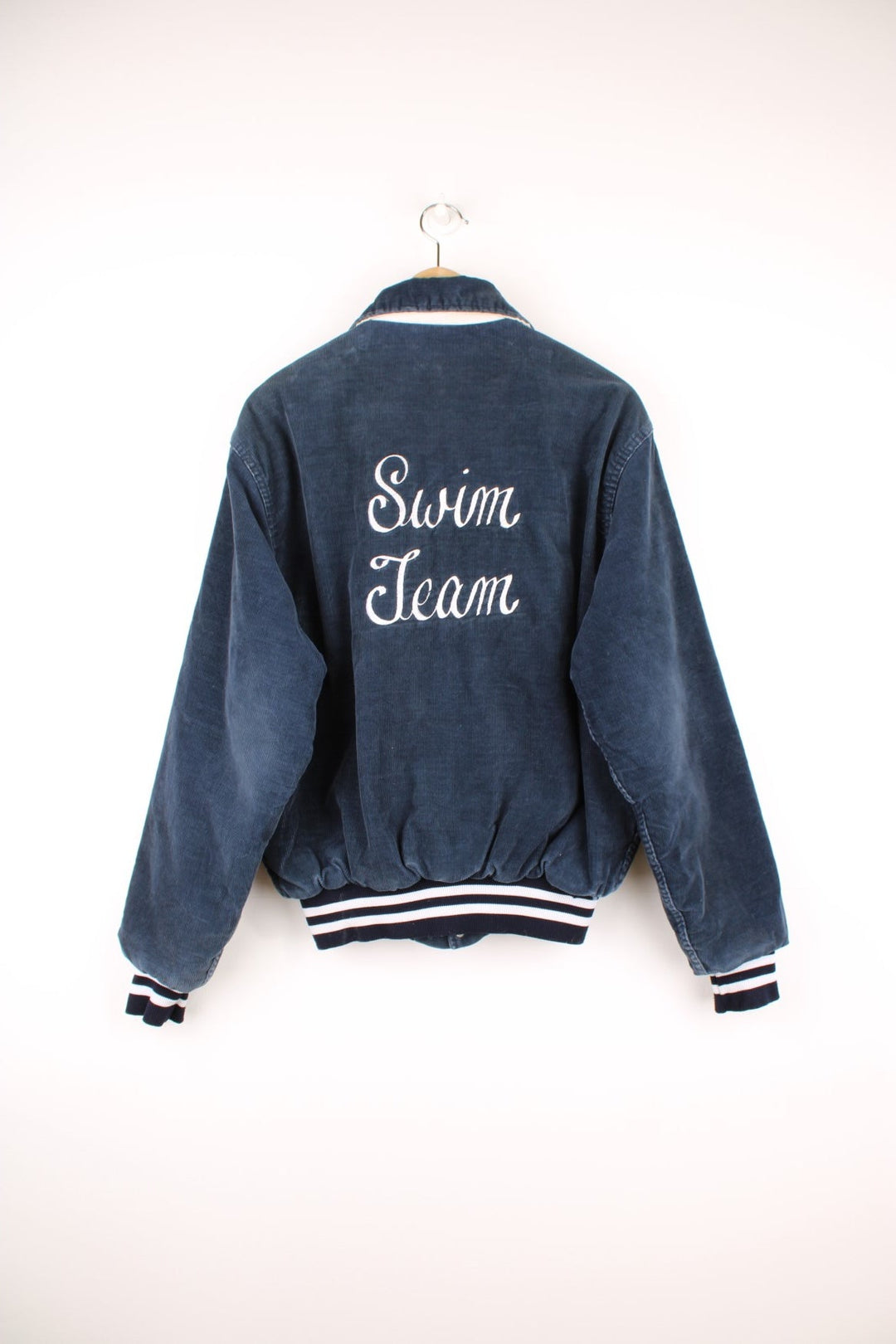 Vintage 90's navy blue corduroy varsity jacket by Rennoc. Features embroidered spell-out motif on the back 'Swim Team' in white, popper buttons fastenings and quilted lining