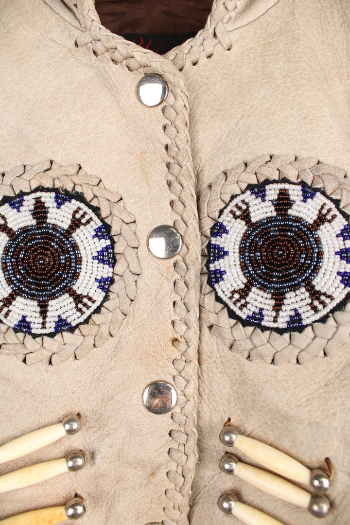 Vintage Native Leather Gilet by 'Hot Leathers' in a tanned colourway, button up, has bones and beades embroiderd on the front alongside the tassels on either side. 