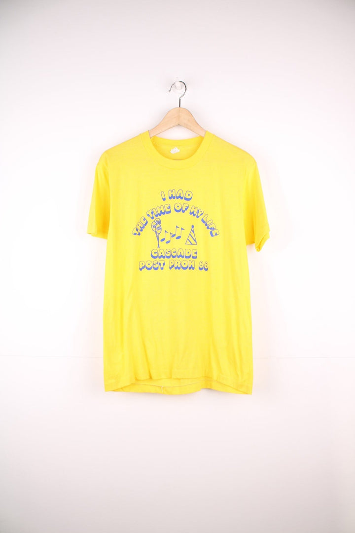 Vintage yellow tee reading 'I had the time of my life - Cascade Prom 88' in blue with balloon, party hat and musical note designs in blue. 