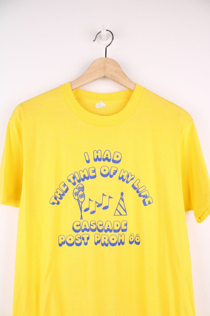 Vintage yellow tee reading 'I had the time of my life - Cascade Prom 88' in blue with balloon, party hat and musical note designs in blue. 