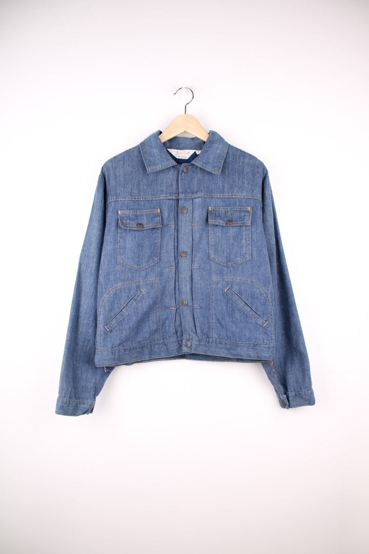 Slantzi-Craft blue denim shirt jacket with a western embroidered back yoke panel, four pockets and button closure. 