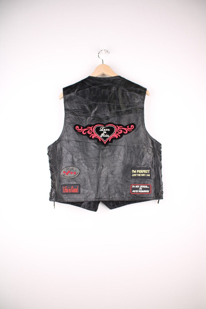 Leather Biker Vest in a black colourway, button up with a v neck collar, and has multiple patches embroidered around the gilet. 