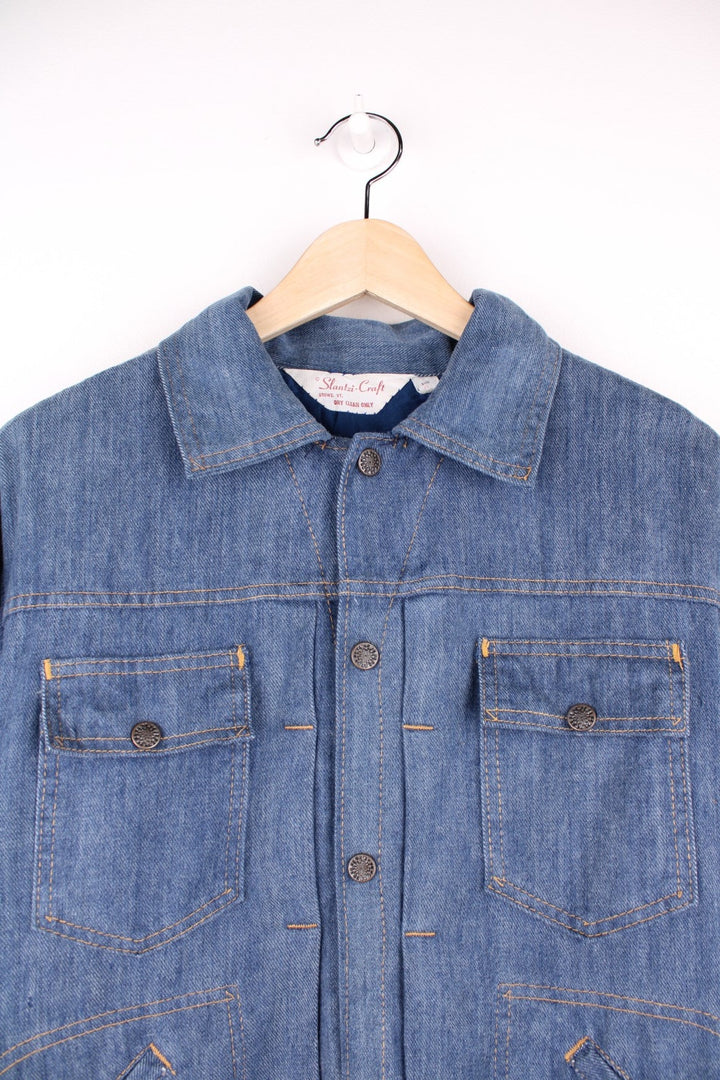 Slantzi-Craft blue denim shirt jacket with a western embroidered back yoke panel, four pockets and button closure. 