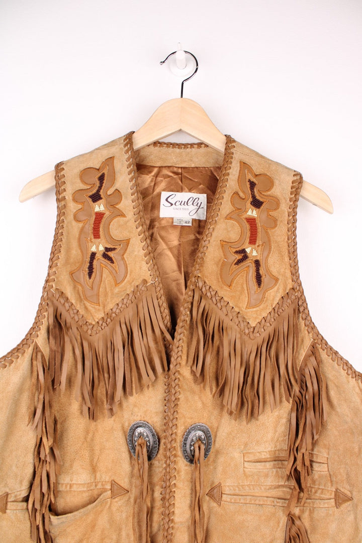 Vintage Scully Western Leather Fringe Waistcoat in a tanned brown colourway, has multiple pockets, embroidered bead native patterns, and has fringe tassels throughout.