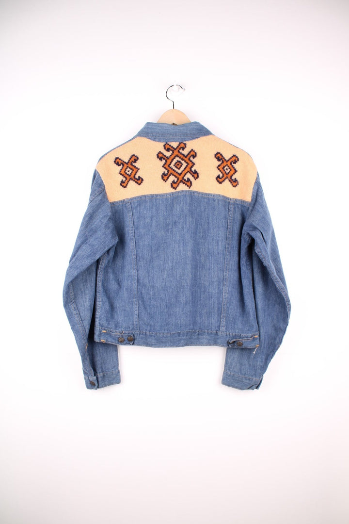 Slantzi-Craft blue denim shirt jacket with a western embroidered back yoke panel, four pockets and button closure. 