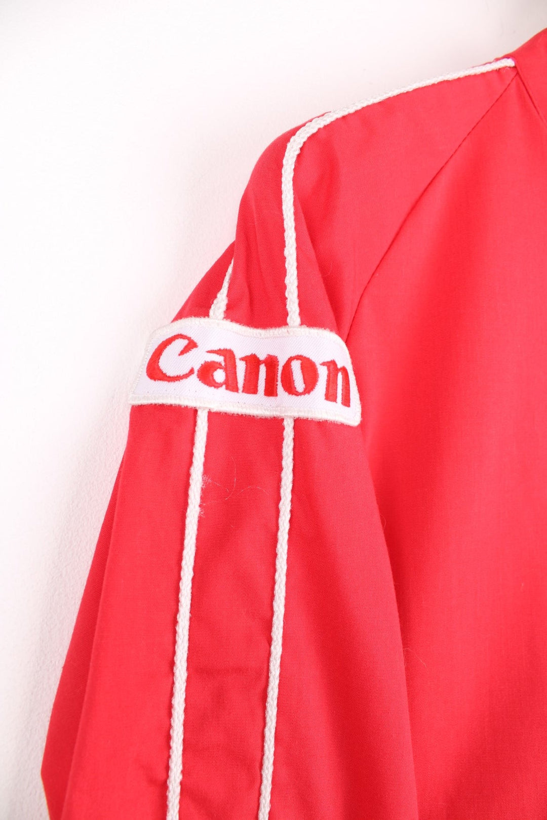 1983 Canon lightweight jacket in red with white piping, embroidered logos, a drawstring at the waist, zip closure and a back graphic of a hot air balloon and text reading 'Albuquerque International Balloon Fiesta - 200 Years of Flight'. 