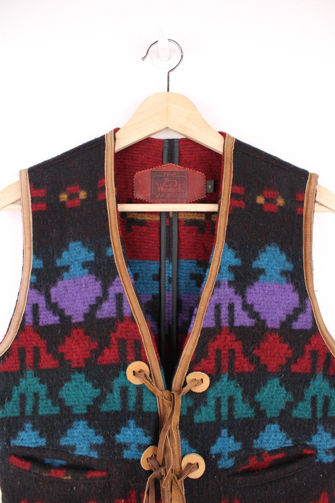 Woolrich patterned vest with geometric designs in red, blue and purple, tie-up closure with brown suede ribbons, and two pockets. 