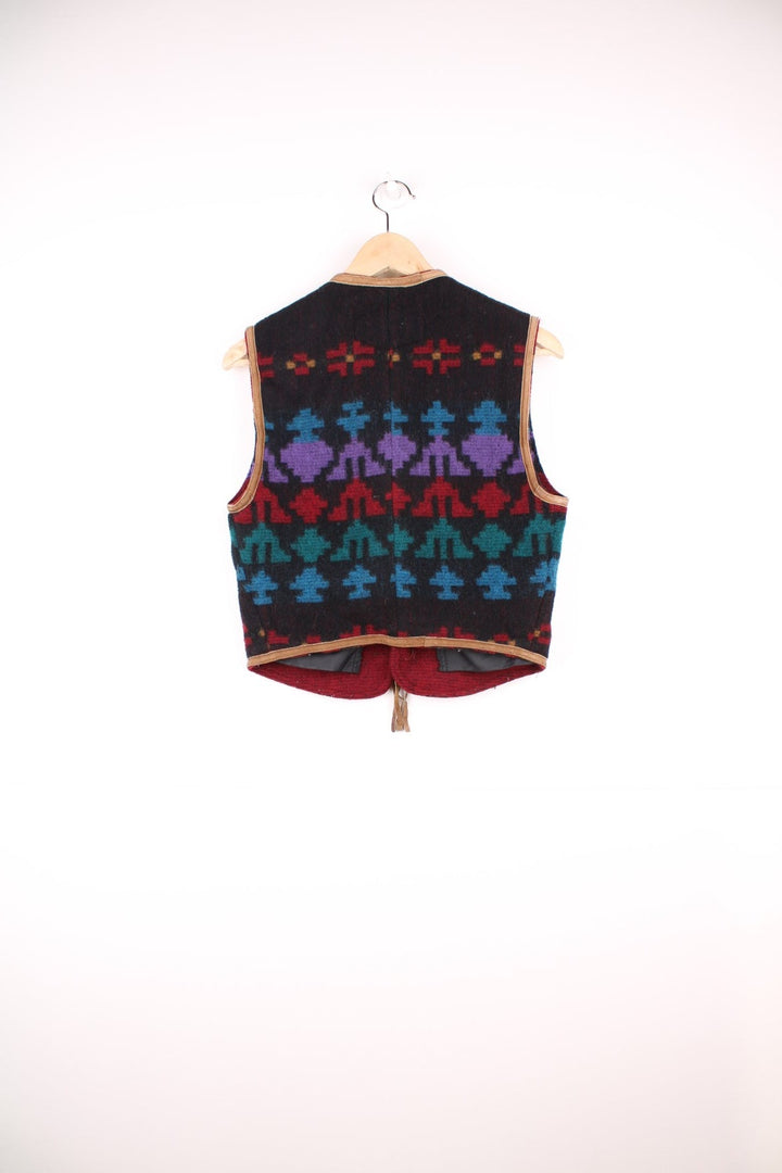 Woolrich patterned vest with geometric designs in red, blue and purple, tie-up closure with brown suede ribbons, and two pockets. 