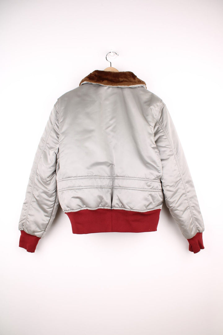 The Line' Denver, Colorado bomber-style goose down ski jacket in silvery grey with red piping, hem and cuffs, a faux fur collar, zip closure and two pockets.