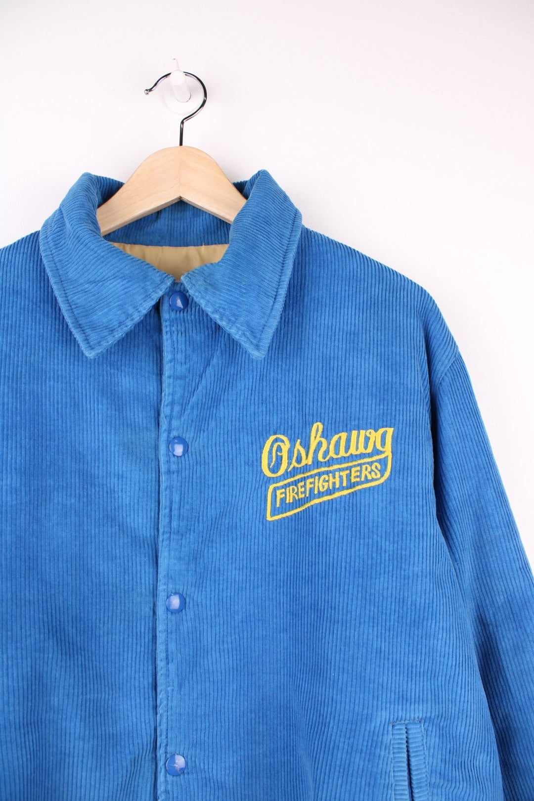 Vintage 80's Oshawa Firefighters Corduroy Varsity Jacket in a blue and yellow colourway, buttons up and has side pockets, insulated with a quilted lining, and has the logos embroidered on the front and right sleeve.