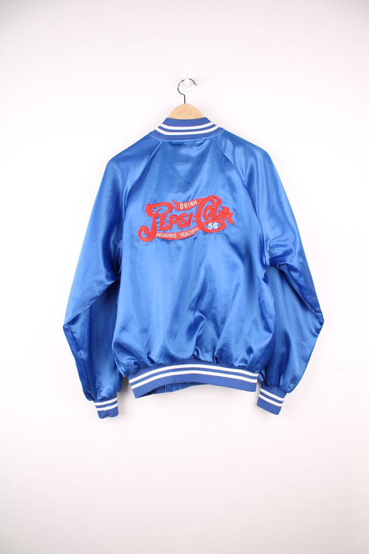 Blue 'Pepsi-Cola' personalised bomber jacket with white striped accents around the collar and cuffs. Snap closure, with the Pepsi-Cola logo embroidered on the chest and back. 