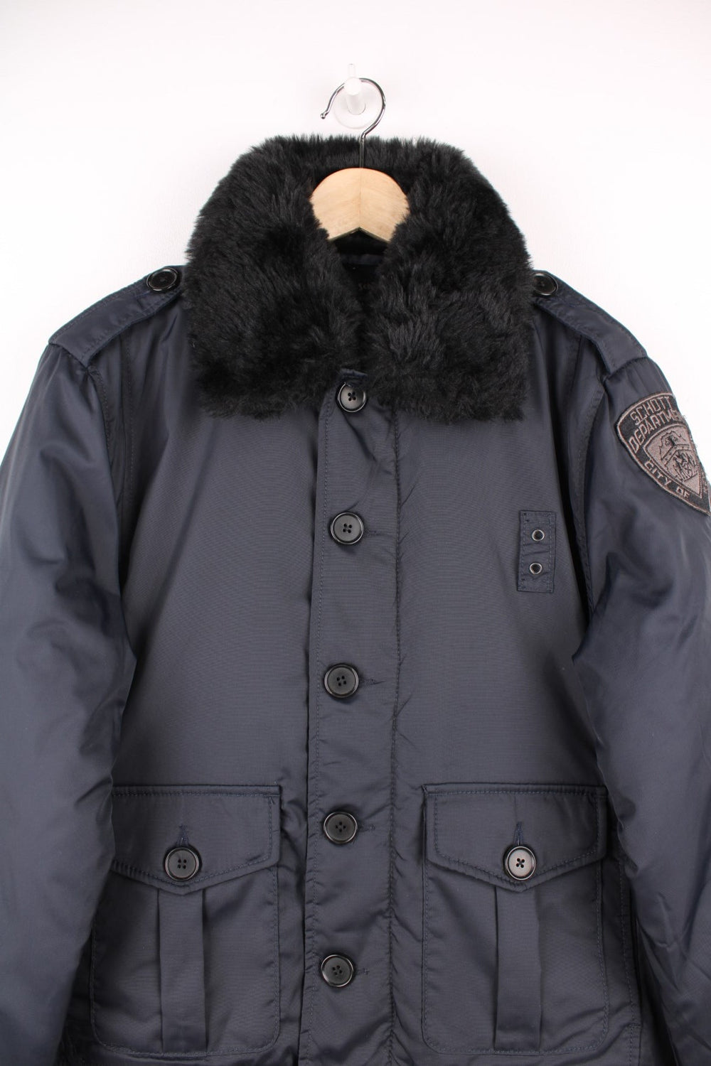 Schott NYC black pilot jacket with a removable faux fur collar, quilt lining, zip and button closure, two buttoned pockets, and epaulette loops on the shoulders. 