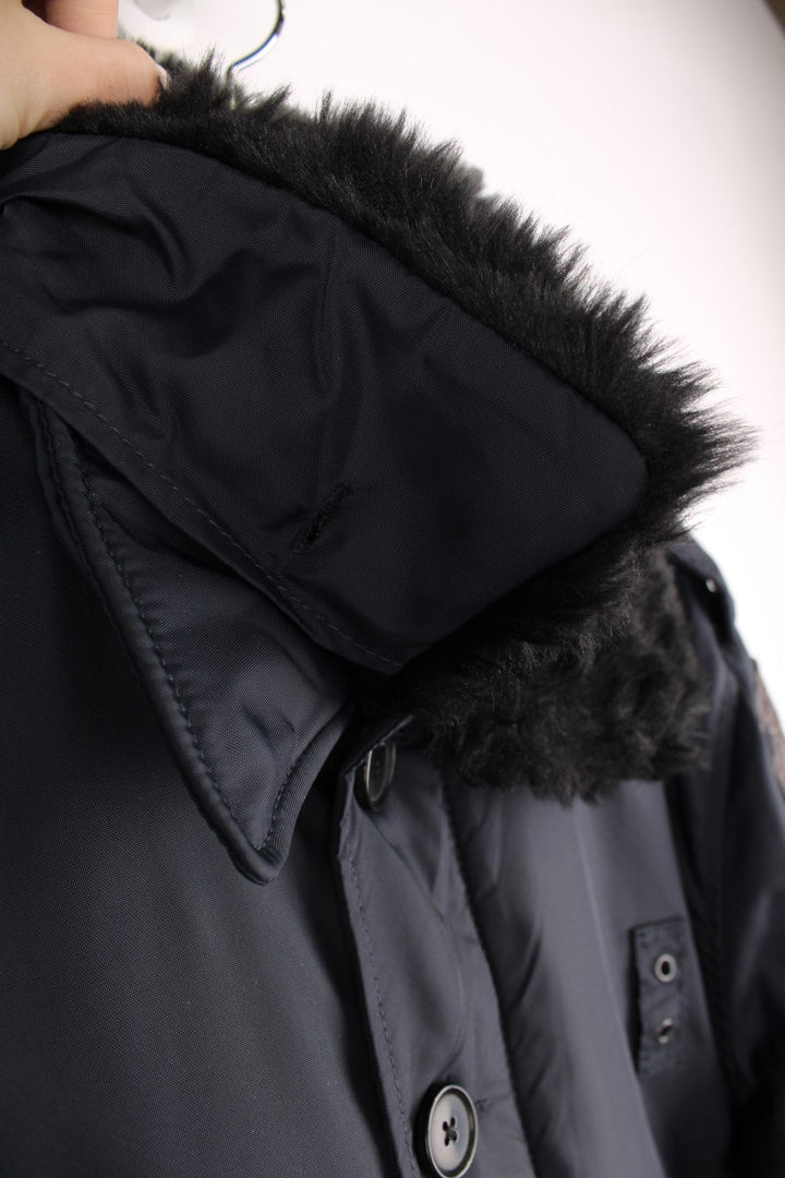 Schott NYC black pilot jacket with a removable faux fur collar, quilt lining, zip and button closure, two buttoned pockets, and epaulette loops on the shoulders. 