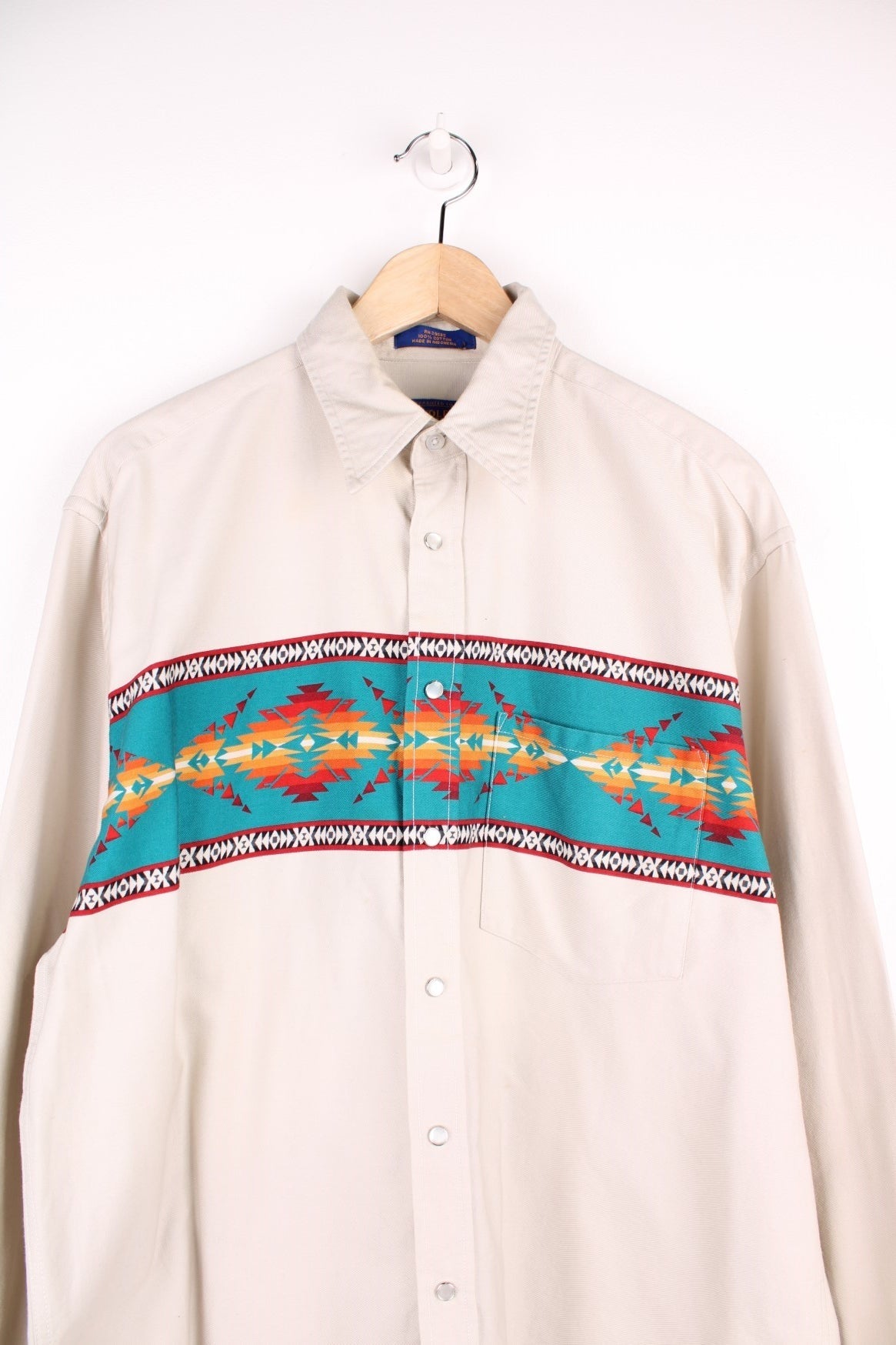 Vintage off-white Pendleton cotton shirt with red and turquoise Western detailing, snap closure, a breast pocket, and a dagger collar. 