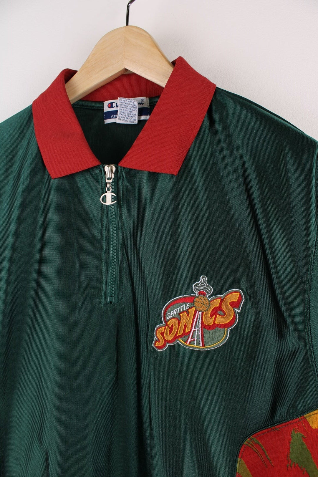 Seattle Supersonics  Polo Warm Up Champion Jersey in a  and red colourway with patterned stripes going down the sides, features quarter zip and has the team logo embroidered on the front and the spell out on the back.