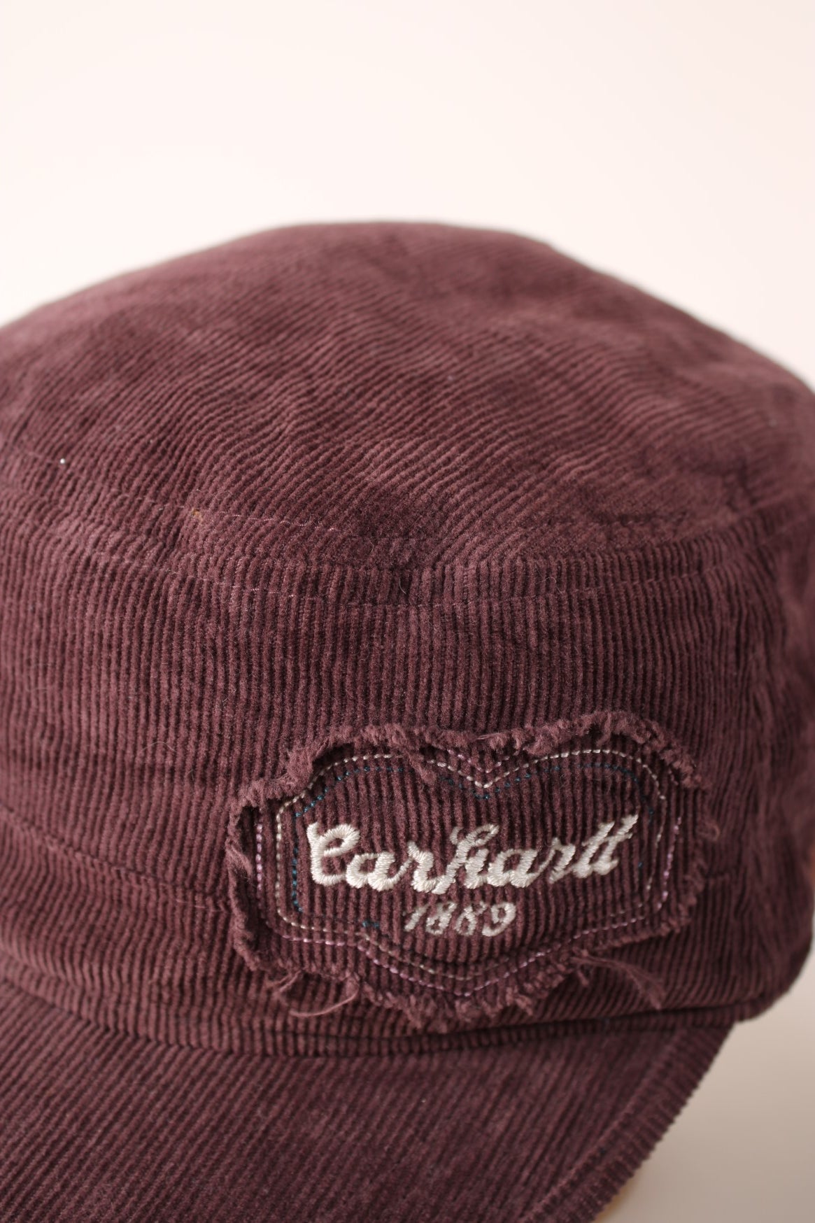 Carhartt 1889 Corduroy Cap in a burgundy courway with logo embroidered on the front and back, and has a adjustable velcro strap.