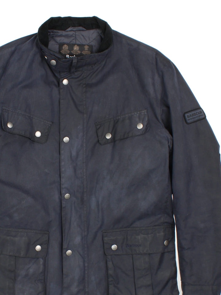 Barbour International Duke Jacket in a blue colourway, zips and buttons up, has multiple pockets, insulated with a quilted lining, and has the logo embroidered on the front and on the left sleeve.