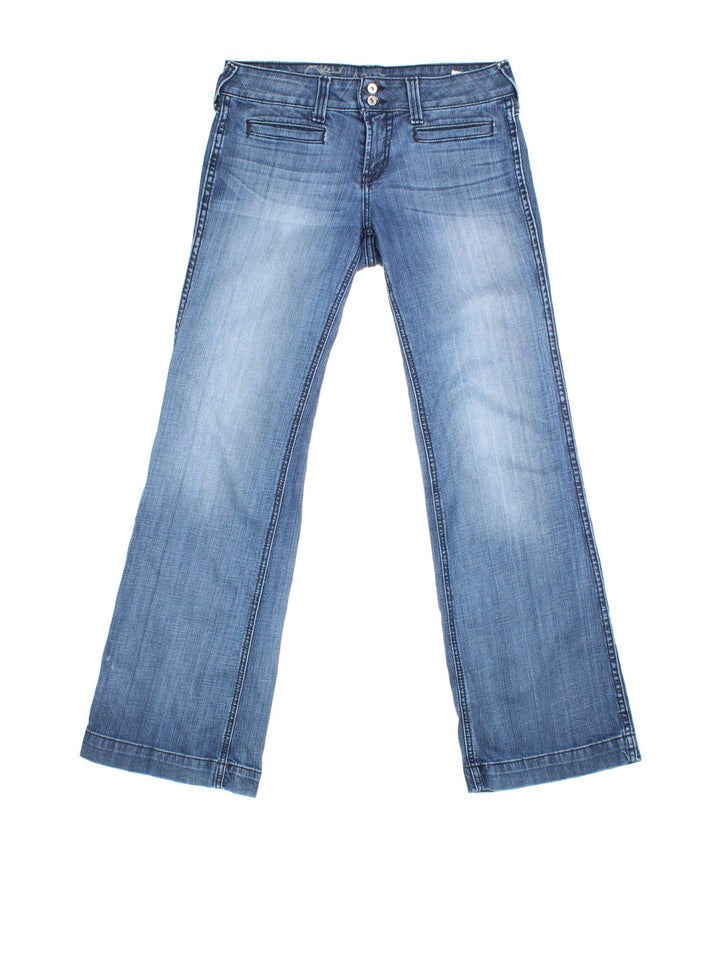 Vintage Y2K Ariat Flared Jeans in blue colourway. Low waisted fit with zip up fly, flared leg and leather logo patch on the back.