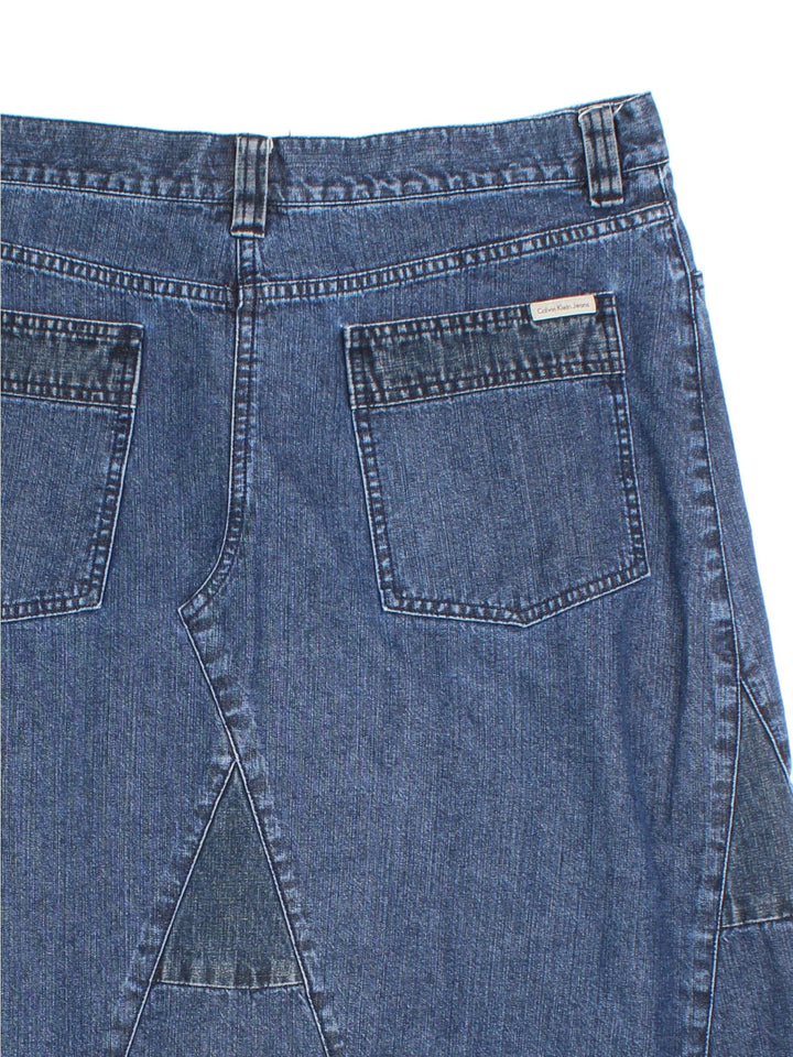 Y2K Calvin Klein Denim Skirt in blue colourway. Button/zip fastening, multi denim panel detailing and branding on back pocket.