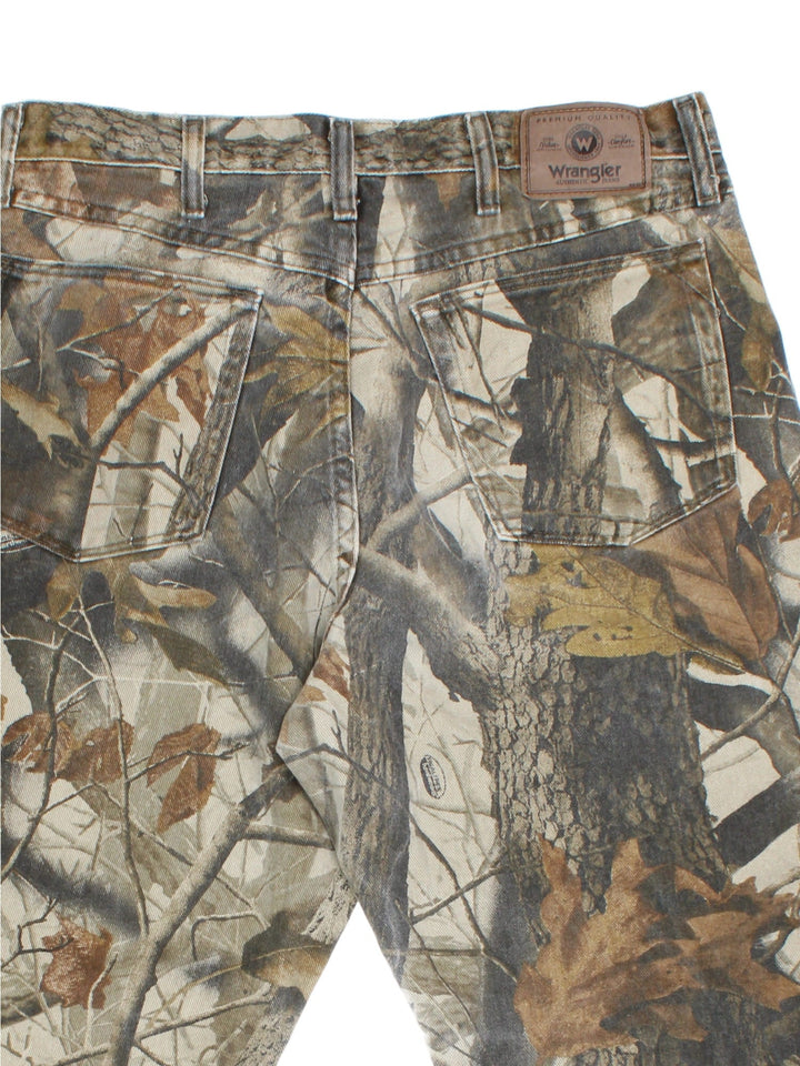 Wrangler Real Tree Camo Jeans in green and brown patterned colourway with multiple pockets, double knee features, and has the logo embroidered on the back.