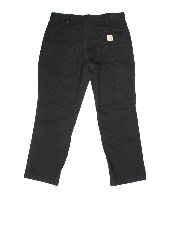 Carhartt Trousers in black colourway. Zip fly fastening with multiple pockets and embroidered patch branding.