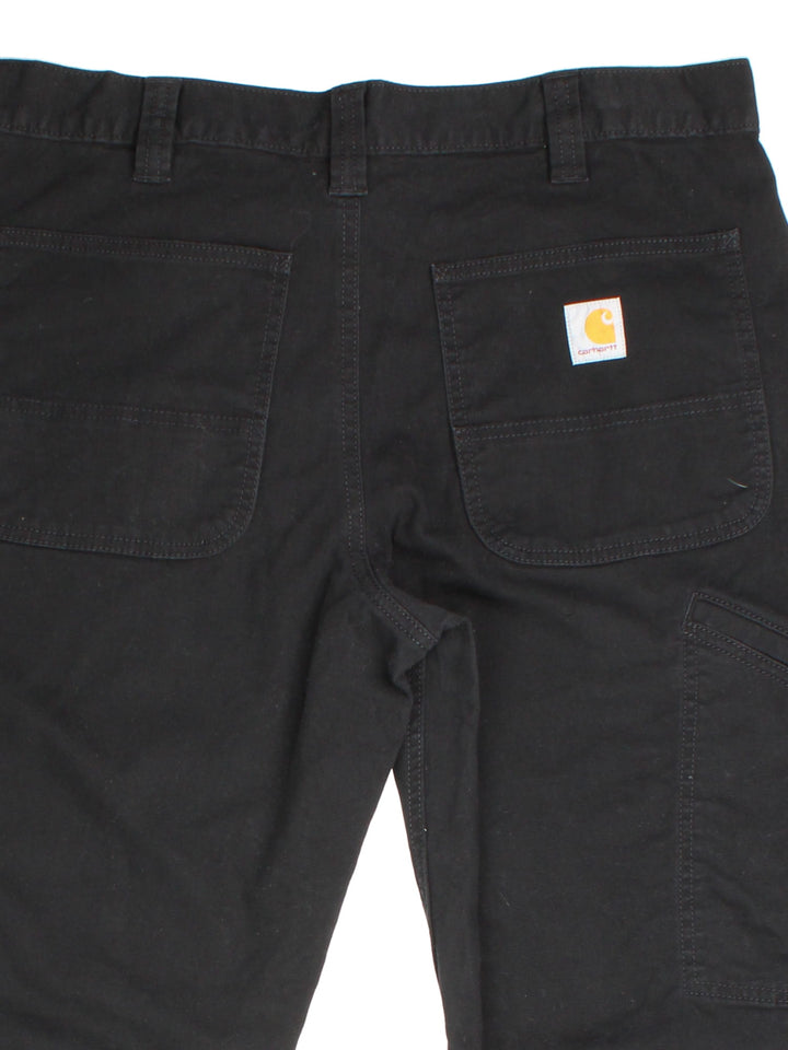 Carhartt Trousers in black colourway. Zip fly fastening with multiple pockets and embroidered patch branding.