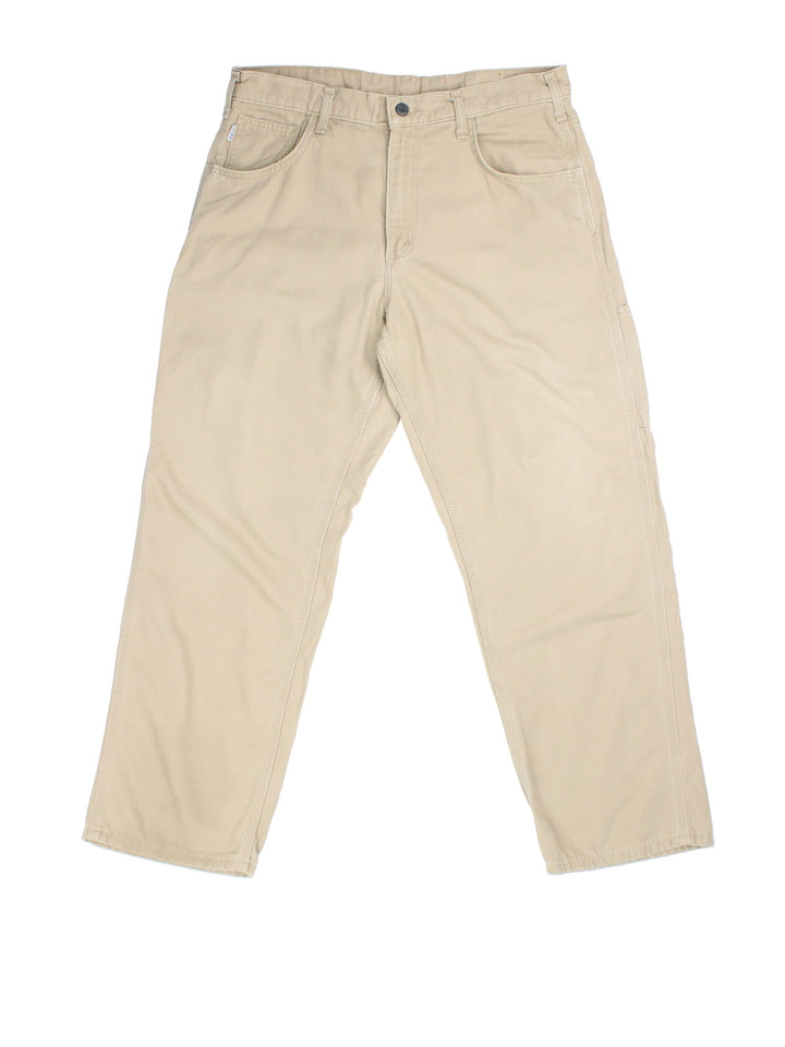 Carhartt Trousers in tan colourway. Zip fly fastening with multiple pockets and embroidered patch branding.