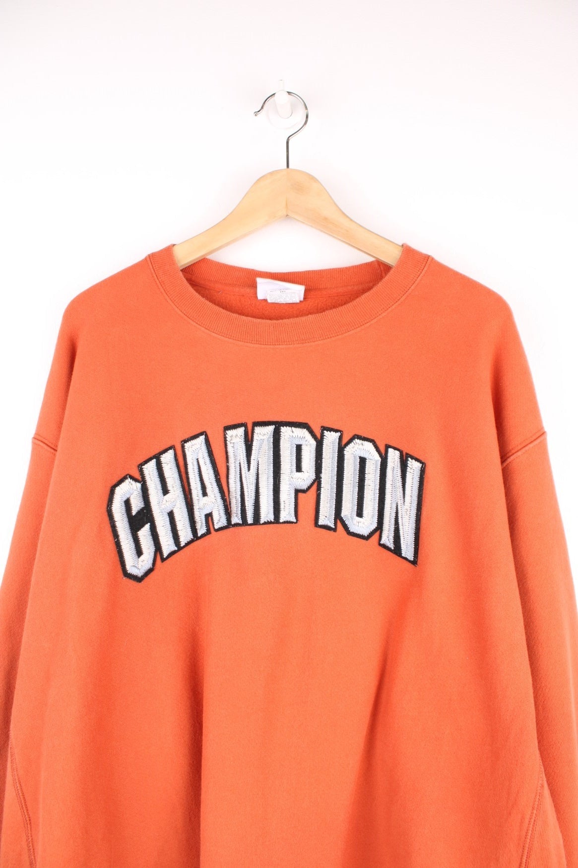 Champion Reverse Weave Sweatshirt in an orange colourway with the spell out logo embroidered across the chest in a metallic style. 