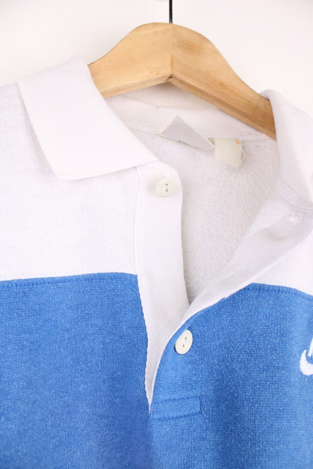 80's Nike Collared Sweatshirt in a white, blue and red block patterned colourway, quarter button up with a collar, and has the logo embroidered on the chest. 