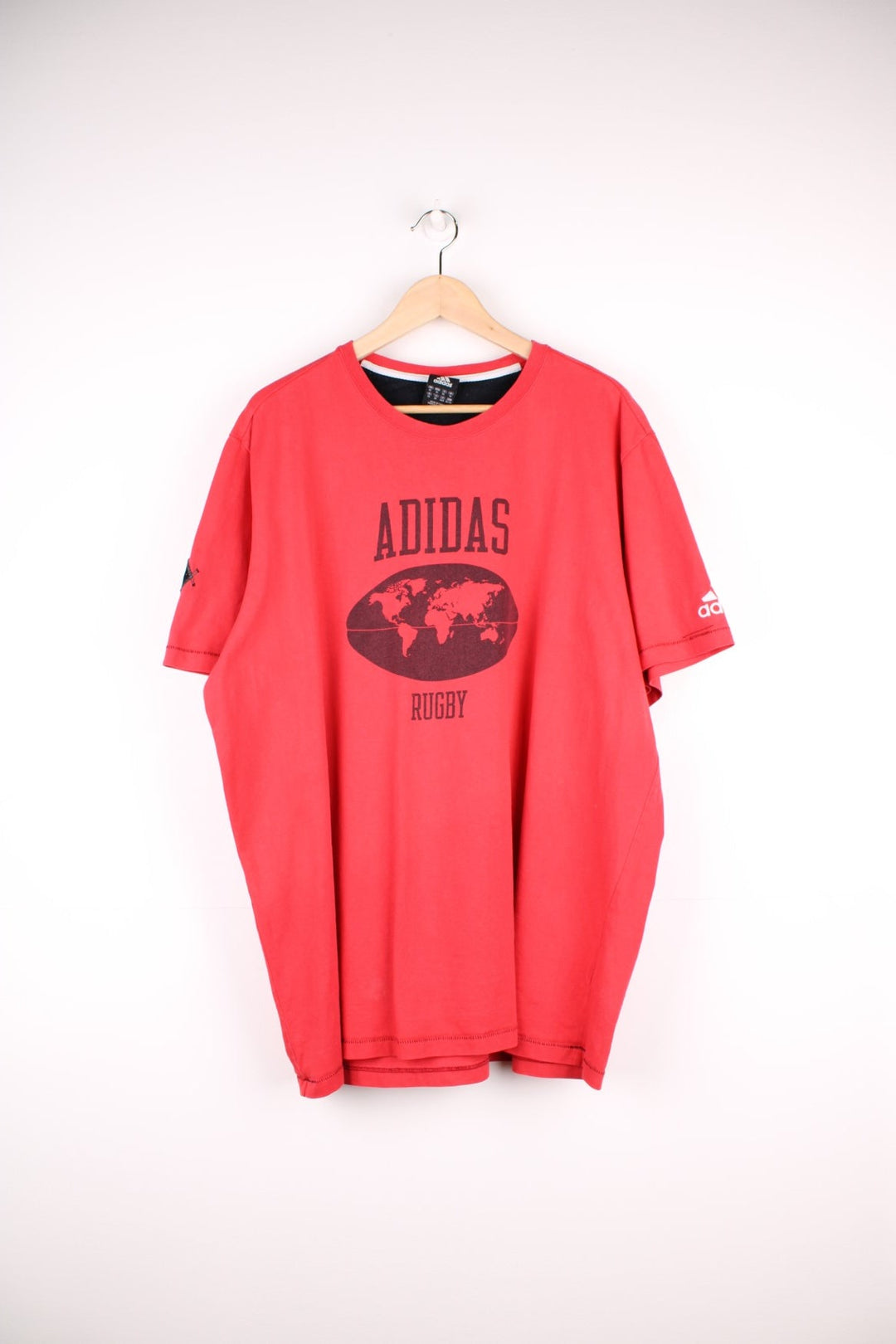 Adidas Rugby T-Shirt in a red and black colourway with the spell out logo and globe graphic printed on the front, and badge logos embroidered on the sleeves. 