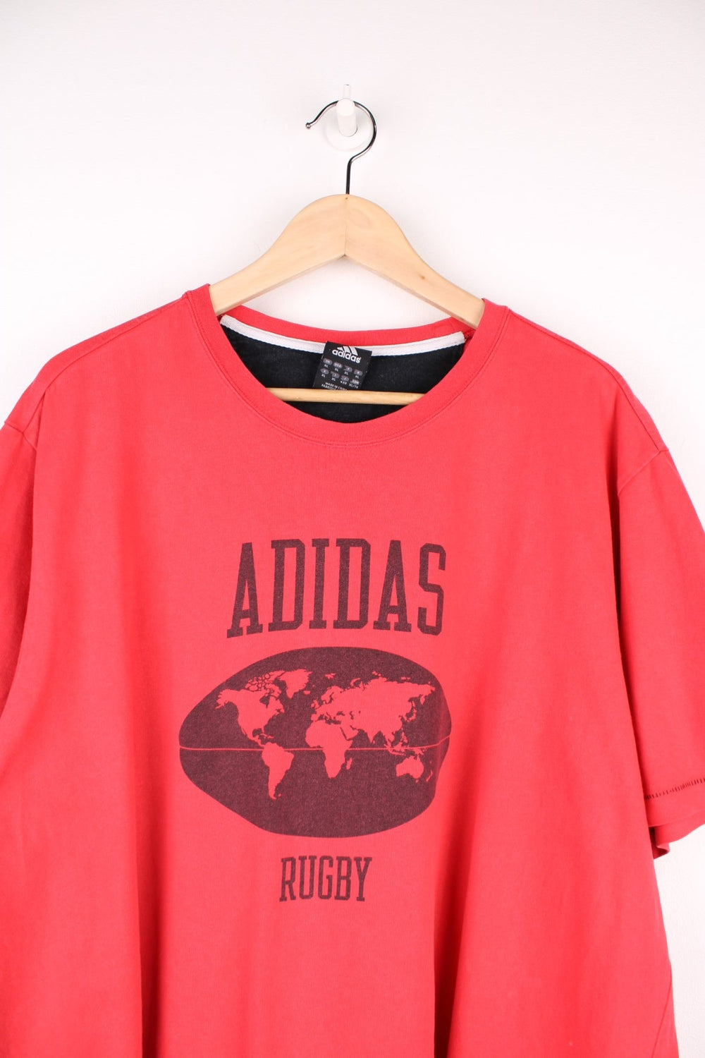 Adidas Rugby T-Shirt in a red and black colourway with the spell out logo and globe graphic printed on the front, and badge logos embroidered on the sleeves. 