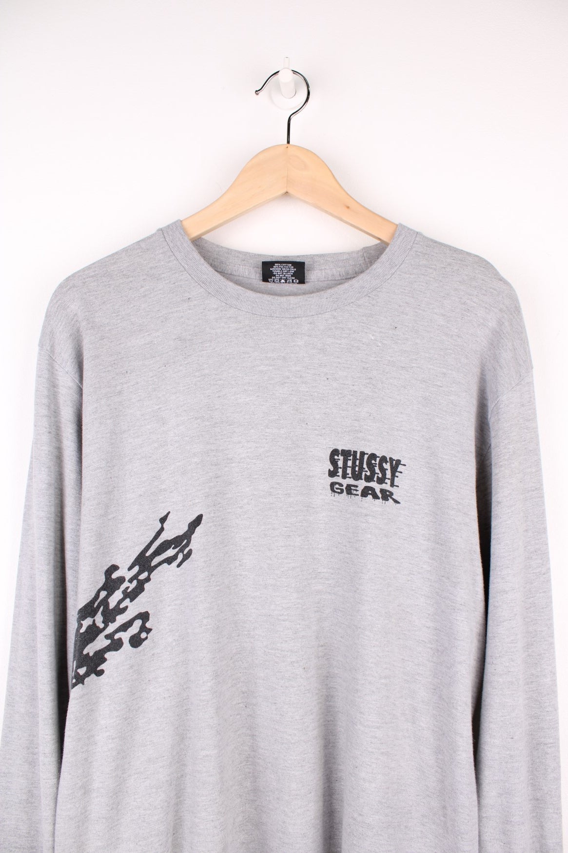 Stussy Gear Longsleeve T-Shirt in a grey and black colourway with the spell out logo printed on the front and motorbike racer going round the side and on the back.