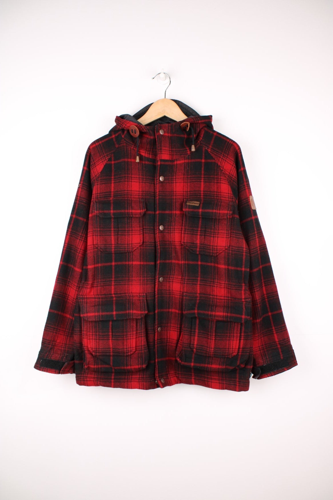 Penfield Trailwear Flannel Jacket in a red and black plaid colourway, zip up with multiple pockets, has a nylon lining, hooded and has the logo embroidered on the front. 