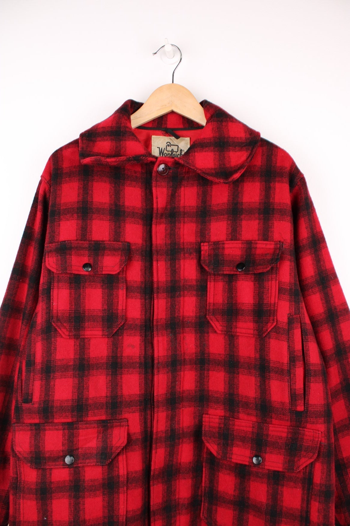 Woolrich Plaid Wool Coat in a red and black colourway, button up with a big collar, multiple pockets, and has a quilted lining. 