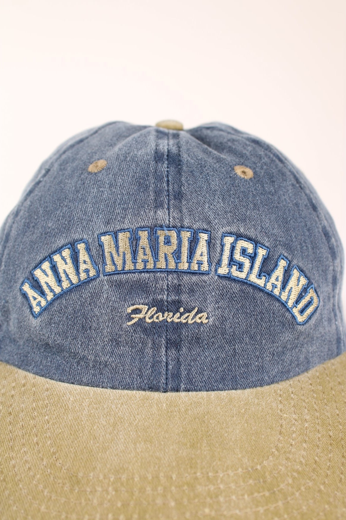 Anna Maria Island Florida Cap in a faded blue and tanned colourway with the spell out logo embroidered on the front, and has a adjustable velcro strap.