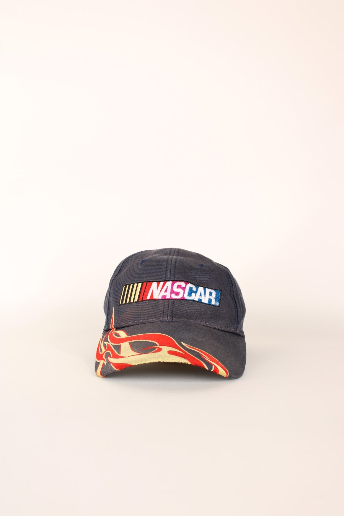 Nascar Racing Cap in a grey colourway with the spell out logo embroidered on the front as well as fire on the front cap, has a adjustable velcro strap.