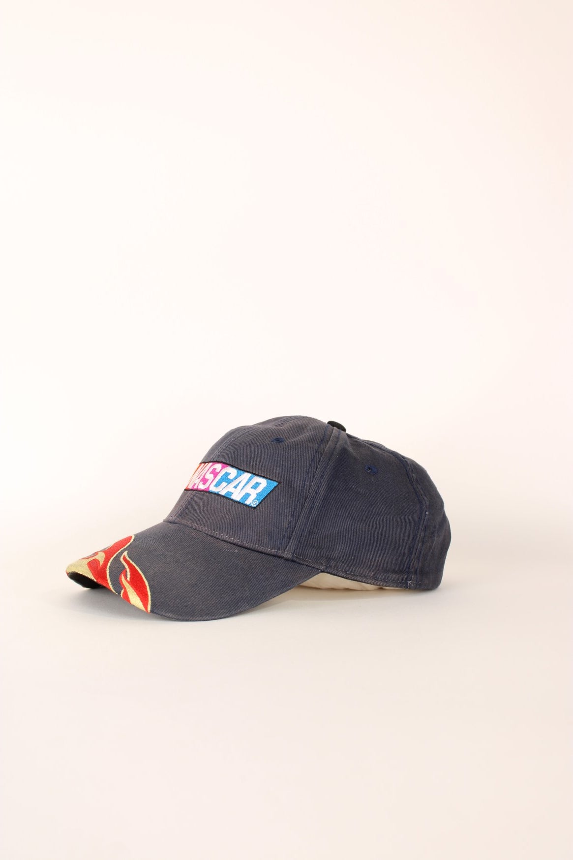 Nascar Racing Cap in a grey colourway with the spell out logo embroidered on the front as well as fire on the front cap, has a adjustable velcro strap.