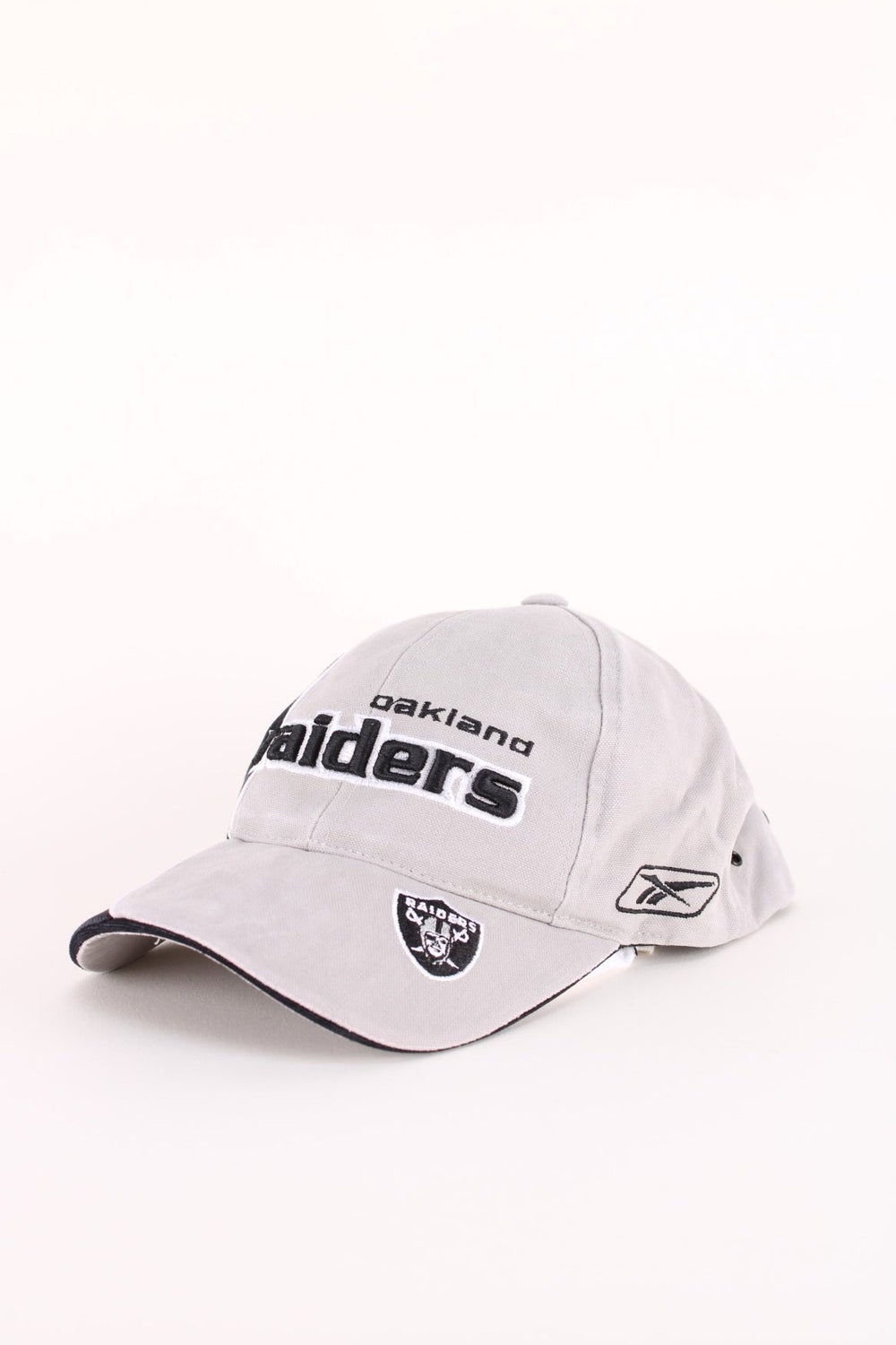 Oakland Raiders NFL Cap in a grey and black colourway with the team logos and spell out embroidered on the hat, and has an adjustable velcro strap.