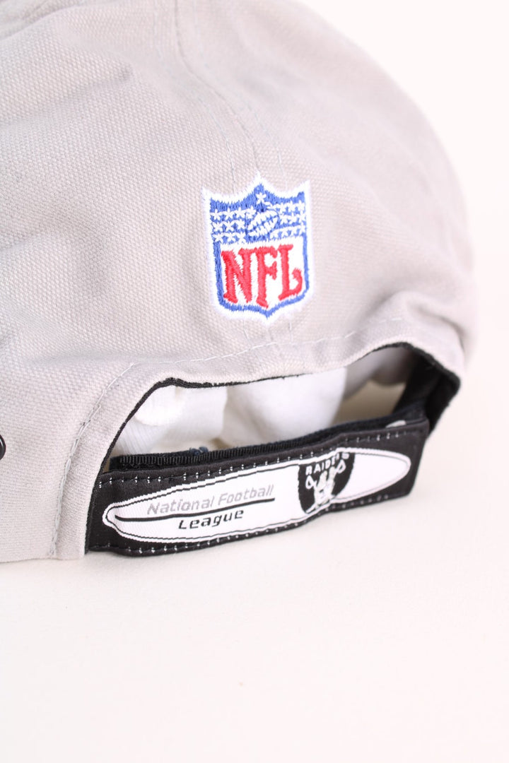 Oakland Raiders NFL Cap in a grey and black colourway with the team logos and spell out embroidered on the hat, and has an adjustable velcro strap.