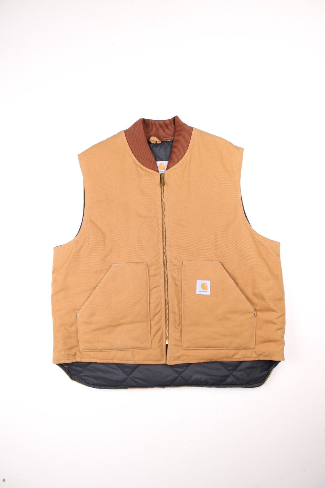 Carhartt Gilet in a tan colourway. Zips up and has side pockets, insulated with a quilted lining, and has the logo embroidered on the front.