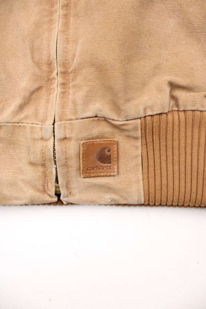 Carhartt Santa Fe Jacket in a tan colourway with a brown corduroy collar. Zips up and has side pockets, and the logo embroidered on the front.