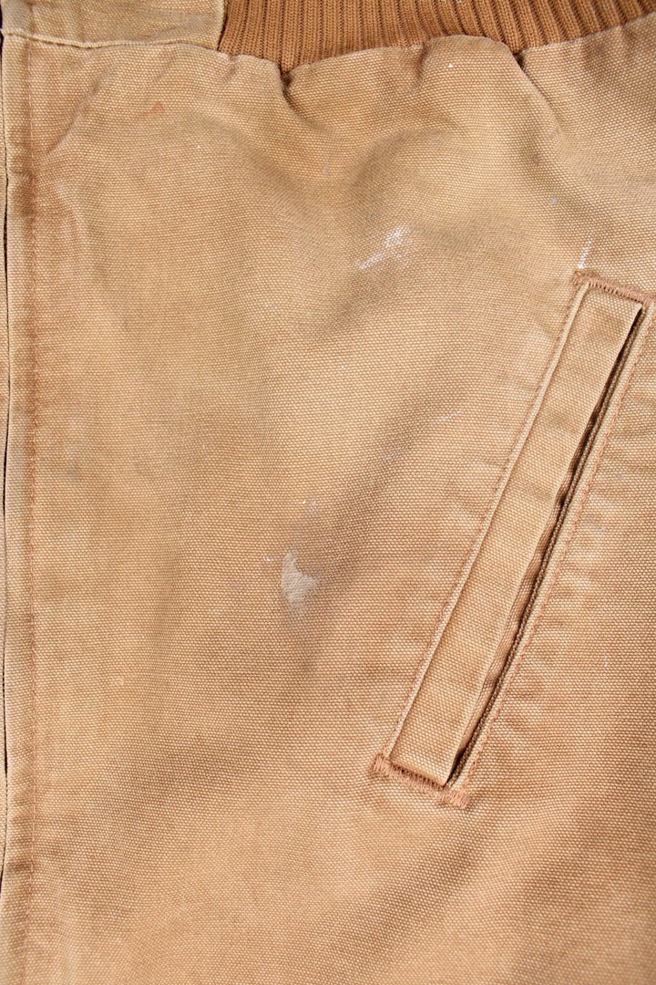 Carhartt Santa Fe Jacket in a tan colourway with a brown corduroy collar. Zips up and has side pockets, and the logo embroidered on the front.