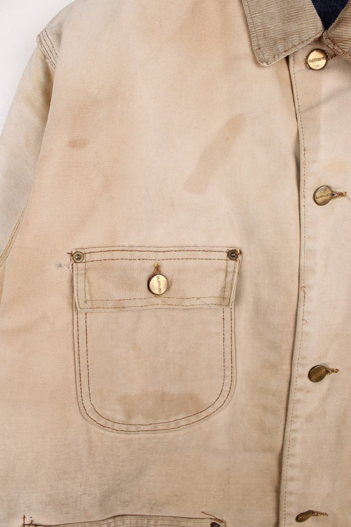 Vintage 70's Carhartt Distressed Chore Jacket in a tan colourway. Buttons up and has multiple pockets, blanket lining, corduroy collar, and has the logo embroidered on the front.