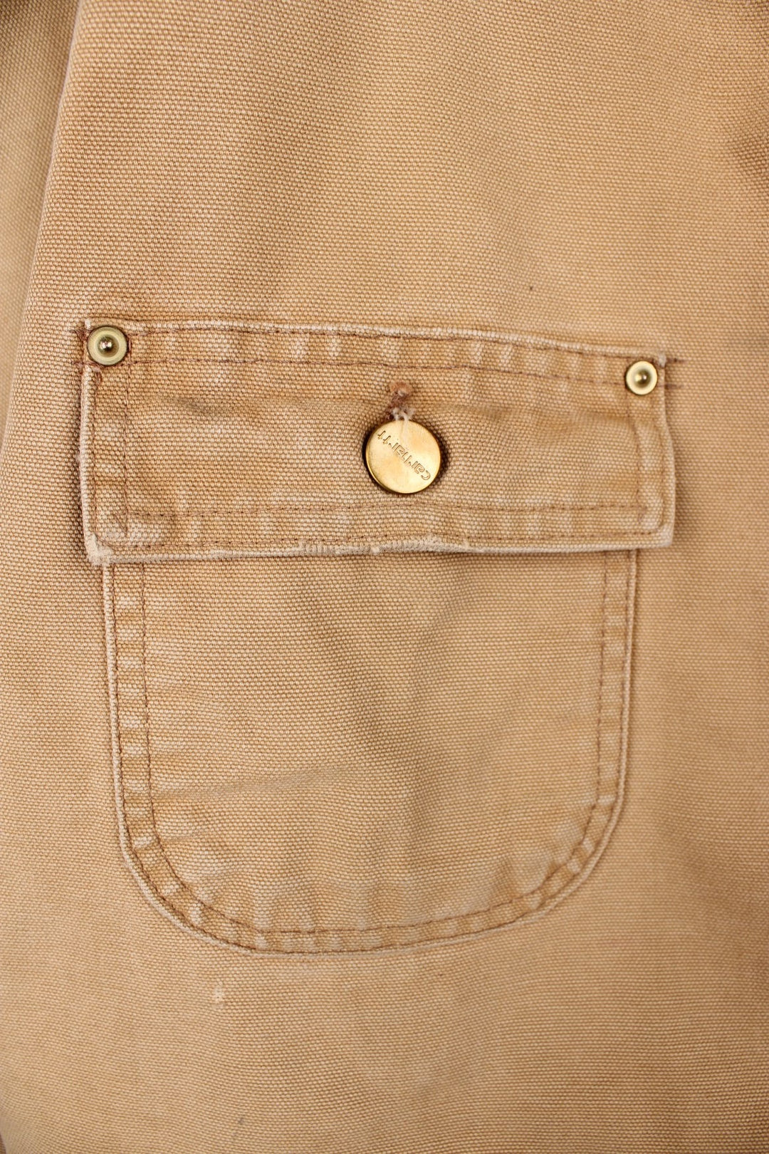 Carhartt Chore Jacket in a tan colourway with a brown corduroy collar. Buttons up and has multiple pockets, blanket lining, and has the logo embroidered on the front.